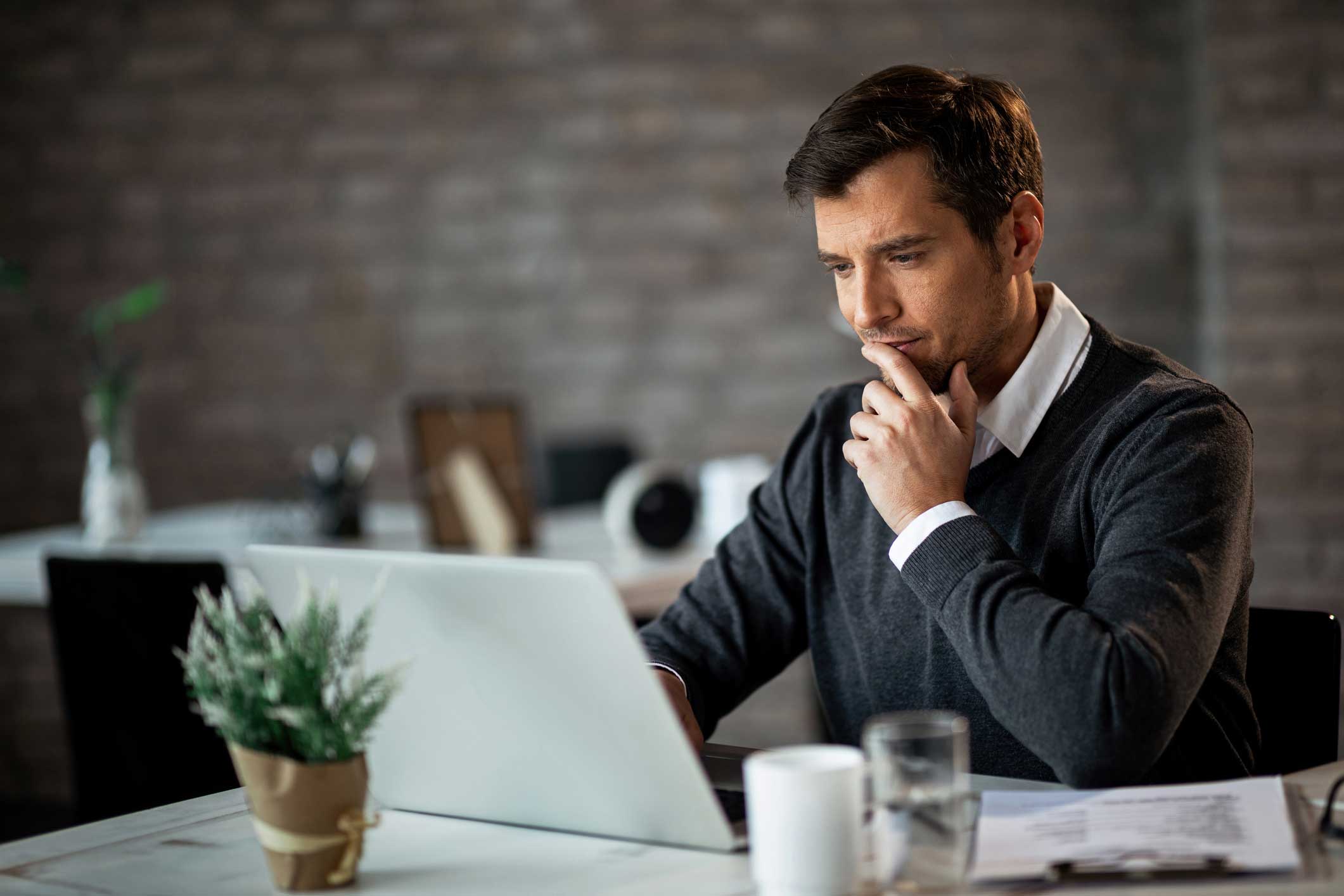 A man looking at a laptop screen concerned