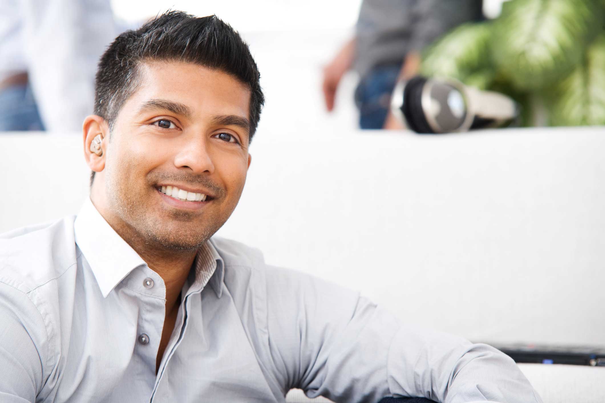 A man with a hearing aid smiling to the camera