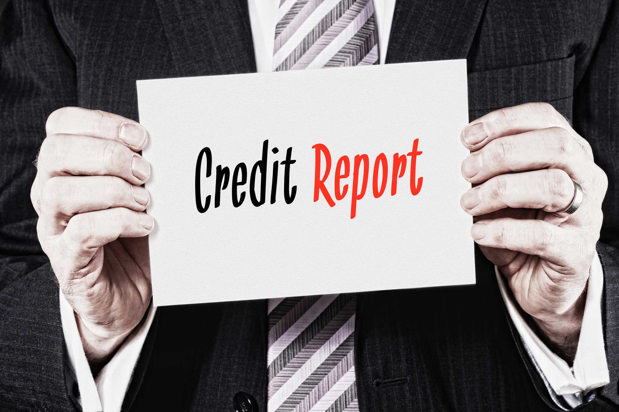 A man in a suit holding a white card that says credit report
