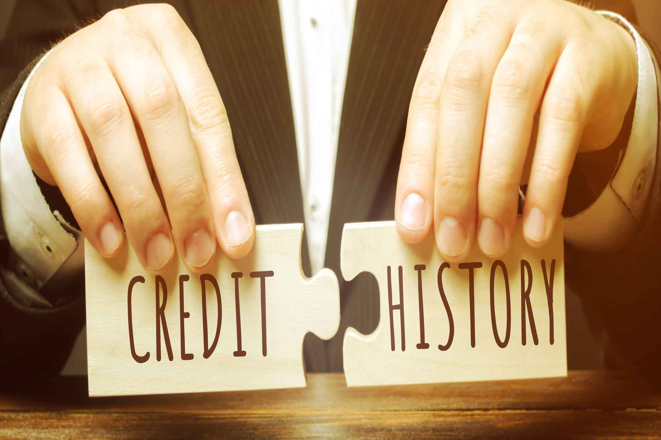 A man holding two connecting jigsaw pieces that say credit and history
