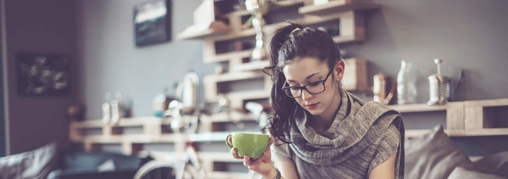 A young woman with a cup of coffee sitting on the couch