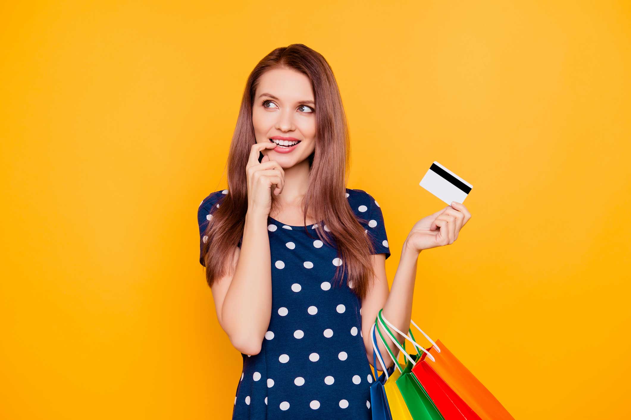 A woman with her credit card in her hand and her other finger at her mouth 