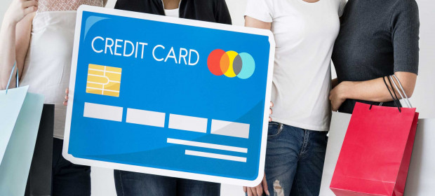 A group of 4 women standing together with shopping bag with a credit card graphic in front of them 